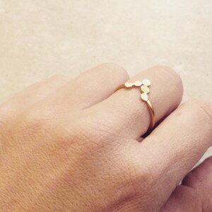 May include: A gold ring with a V-shaped design made of small, round, connected pieces.