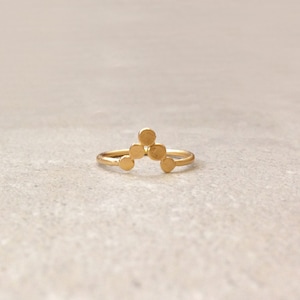 May include: A gold ring with a geometric design of five small circles arranged in a triangular shape.