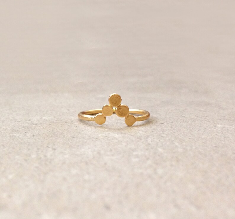 May include: A gold ring with a geometric design of five small circles arranged in a triangular shape.