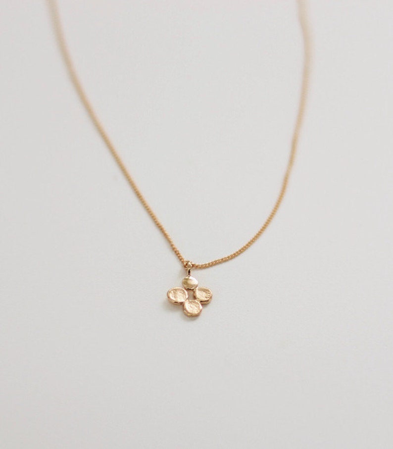 K&ouml;nnte beinhalten: Eine goldene Halskette mit einer zarten Kette und einem kleinen Anh&auml;nger aus vier verbundenen Kreisen.