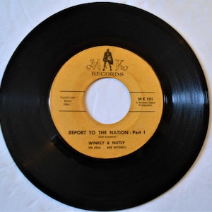 May include: Black vinyl record with a yellow label. The label has the text "MAK RECORDS" in black lettering. The record title is "REPORT TO THE NATION - Part I" by "WINKLY & NUTLY".