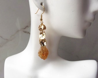 May include: Gold dangle earrings with a cluster of gold discs and a large, faceted, amber-colored gemstone.