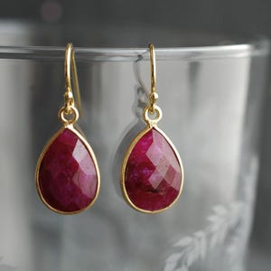 Op de afbeelding: Een paar gouden oorbellen met druppelvormige robijnen.