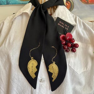 May include: Black necktie with gold painted broken heart pendants reading "Best Friends". The tie is styled on a white collared shirt. A tag reads "Girl in a Whirl UK".
