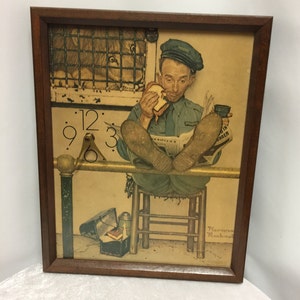 Peut inclure: Une estampe encadrée de Norman Rockwell représentant un homme assis sur un tabouret, mangeant un sandwich et lisant un journal. L'homme porte un uniforme bleu et une casquette. Un lion est visible dans une cage derrière lui. L'estampe comprend un cadran d'horloge avec des chiffres romains et une aiguille dorée.