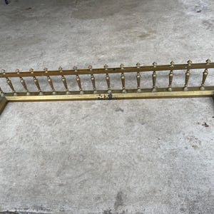 Può includere: Un parascintille per camino in ottone con un design decorativo. Il parascintille è in metallo e ha una finitura dorata. È progettato per proteggere il pavimento da scintille e braci provenienti dal camino.