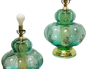 Può includere: Un paio di lampade da tavolo vintage in vetro verde con motivi floreali. Le lampade hanno una base rotonda e bulbosa e una base in metallo dorato.