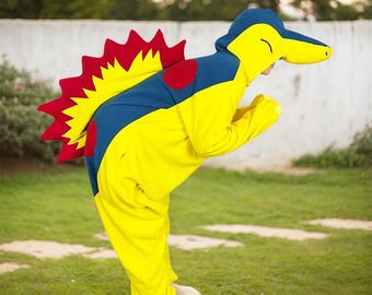 May include: Yellow, blue, and red plush costume of a cartoon character with a spiky tail and a large head. The costume has a zipper in the front and a hood.