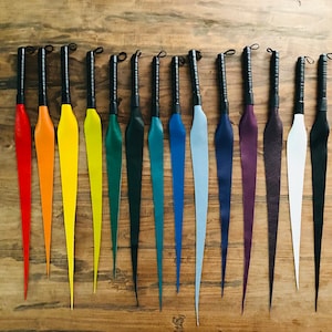 May include: A set of 14 colorful leather whips with black handles. The whips are arranged in a rainbow pattern, with red, orange, yellow, green, blue, indigo, and violet.
