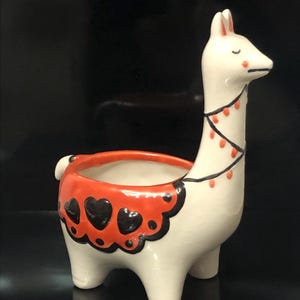 Maceta de cerámica hecha a mano con forma de llama de color naranja y colores vibrantes.