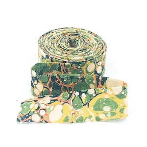 May include: A roll of green, orange, and white fabric ribbon with a marbled pattern. The ribbon is rolled up and has a few inches of the ribbon unrolled.