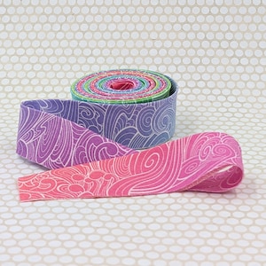 May include: A roll of fabric ribbon featuring a continuous pattern of white swirling wave-like lines against a gradient background that transitions from purple to pink. The ribbon is coiled into a circular shape with the end extending outward.