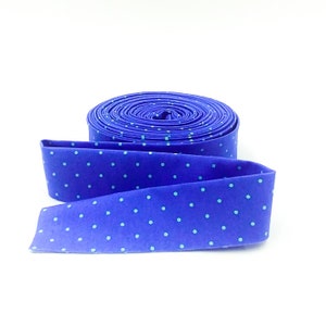 May include: A roll of blue fabric with white polka dots. The fabric is rolled up and tied with a ribbon.