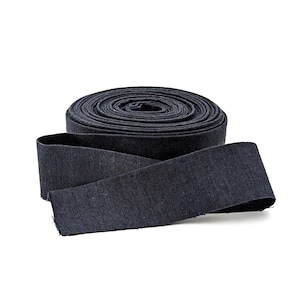 May include: A roll of dark navy blue fabric ribbon with a visible woven texture. The ribbon is coiled into a tight cylinder with one end extending outward, showcasing the flat, flexible material and the consistent deep blue color throughout.
