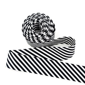 May include: A roll of black and white striped ribbon. The ribbon is unrolled, revealing a portion of the striped pattern. The ribbon is made of a fabric material and is suitable for crafts and decorative purposes.