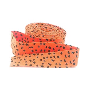 May include: A roll of orange fabric with a black star pattern. The fabric is rolled up and tied with a ribbon.
