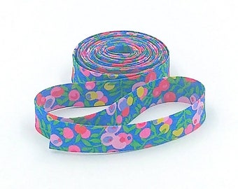 May include: A roll of blue fabric ribbon with a floral print featuring pink, yellow, and green flowers.