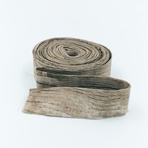 May include: A roll of brown fabric with a woodgrain pattern. The fabric is rolled up and tied with a brown ribbon.