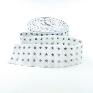 May include: A roll of white fabric with a gold star pattern. The fabric is rolled up and tied with a white ribbon.