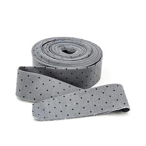 May include: A roll of gray fabric ribbon featuring a repeating pattern of small black polka dots. The ribbon is wound into a tight circular coil with one end extending outward, displaying the consistent dotted design across the entire surface.