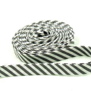 May include: A roll of bias tape in a gray and white striped pattern. The tape is coiled, with a portion unrolled and extending outward. The fabric has a diagonal stripe design, suitable for sewing and crafting projects.