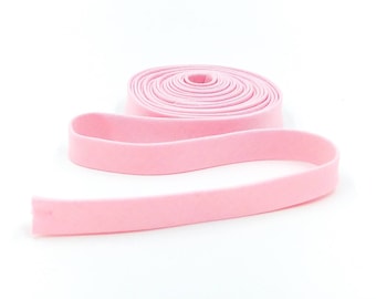 May include: A pink elastic band rolled up on a white background.