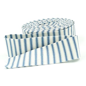 May include: A roll of blue and white striped fabric ribbon. The ribbon is unrolled, revealing the pattern of vertical blue stripes against a white background. The fabric is tightly rolled, with the end of the ribbon extending outward.