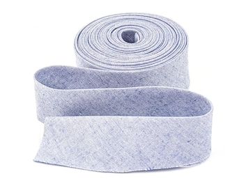 May include: A roll of light blue fabric ribbon, partially unrolled, against a white background. The ribbon has a textured appearance and is tightly wound in a circular shape. The unrolled portion lies in a gentle curve.