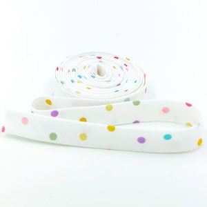 May include: A roll of white elastic with colorful polka dots. The elastic is rolled up and the polka dots are visible on the outside of the roll.