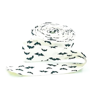 May include: A roll of white fabric ribbon with a black bat pattern.