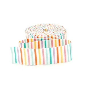 May include: A roll of flat elastic ribbon featuring a repeating vertical stripe pattern in shades of orange, light blue, yellow, and lavender on a white background. The fabric band is coiled into a circular shape with one end extending outward.