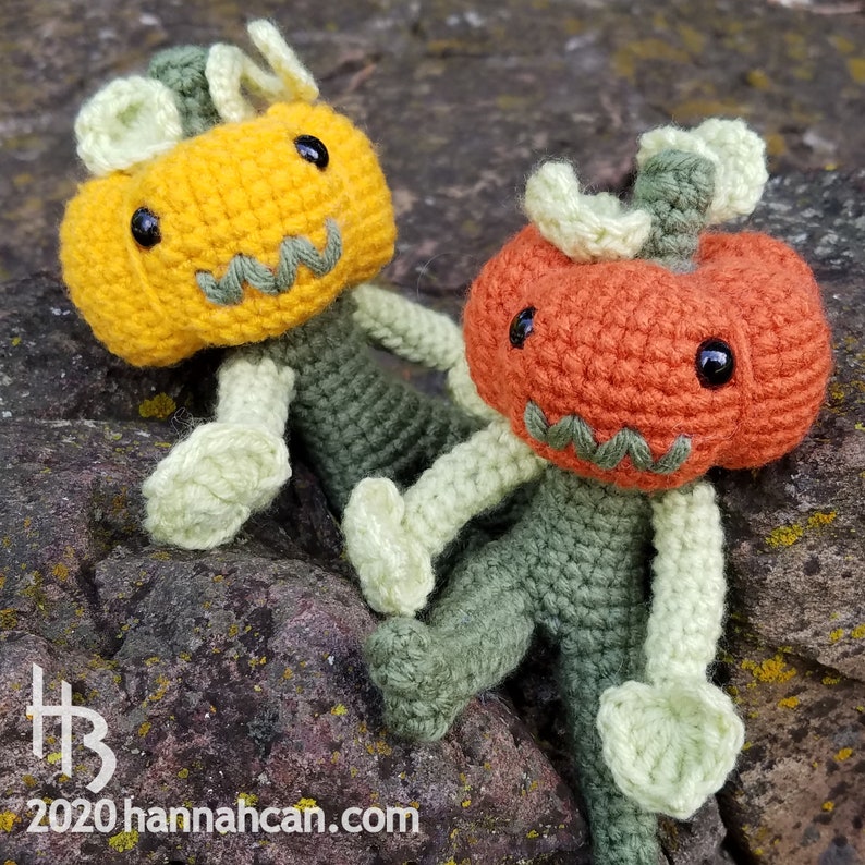 May include: Two crocheted pumpkin characters with green bodies and orange and yellow faces. The pumpkins have stitched on eyes and mouths.