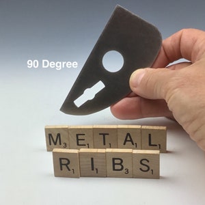 May include: A metal tool with a hole and a slot, labeled "90 Degree". The tool is held in a hand above a row of wooden tiles spelling out "METAL RIBS".