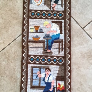May include: Handmade tapestry depicting three scenes of artisans at work. The top scene shows a glassblower, the middle a potter, and the bottom a blacksmith. The tapestry is framed with a brown border and decorative stitching.