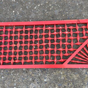 May include: Red wooden lattice panel with a diamond pattern and a decorative fan-shaped design in the corner.