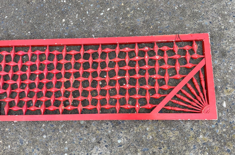 May include: Red wooden lattice panel with a diamond pattern and a decorative fan-shaped design in the corner.