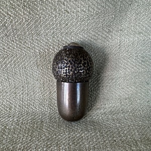 May include: A silver bottle stopper with a textured, round top and a smooth, cylindrical base.