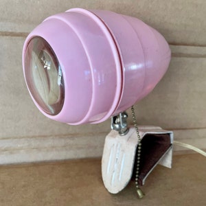 May include: A pink vintage desk lamp with a clamp base and a clear glass shade. The lamp has a chain pull switch and a white cord.