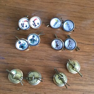 May include: A collection of ten vintage gold-toned buttons with various images, including a toucan, a bird, a man in a top hat, a rabbit, and a plain button.