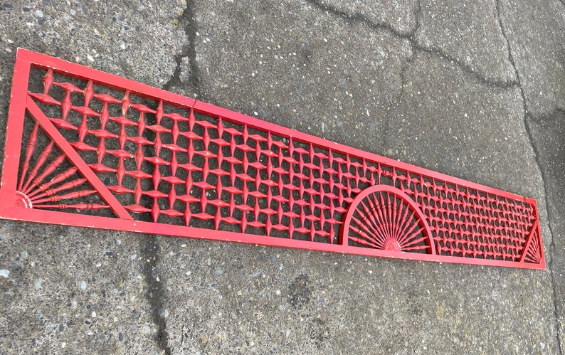 May include: A long, red wooden lattice panel with a geometric design. The panel features two fan-shaped designs at each end.