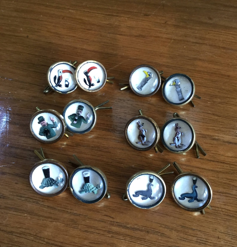 May include: Set of 10 vintage glass button cufflinks with various images, including a toucan, a kangaroo, a leprechaun, a turtle, and a seal. The cufflinks are gold-toned and have a clear glass dome.