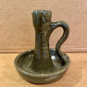 May include: A green ceramic candlestick with a single candle holder and a small dish at the base.