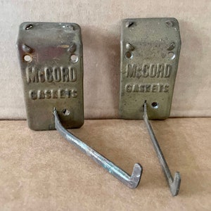 May include: Two vintage metal McCord Gaskets hooks with a gold finish and a bent metal hook.