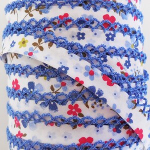 May include: A roll of blue and white floral trim with a crocheted edge. The trim is ideal for adding a touch of elegance to any project.