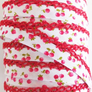 Peut inclure: Bobine de galon &eacute;lastique blanc avec une bordure en crochet rouge et un motif r&eacute;p&eacute;t&eacute; de cerises roses.