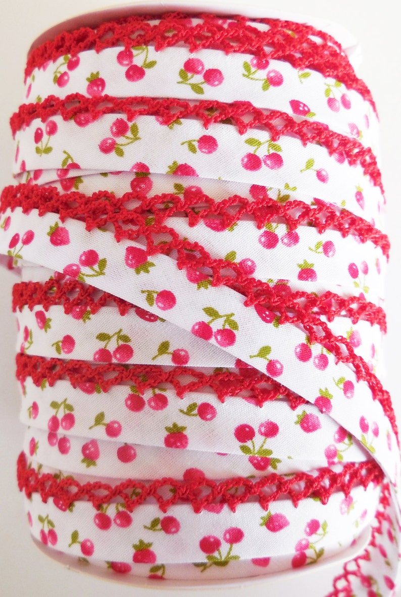 Peut inclure: Bobine de galon &eacute;lastique blanc avec une bordure en crochet rouge et un motif r&eacute;p&eacute;t&eacute; de cerises roses.