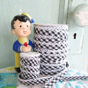 May include: Black and white gingham ribbon with white crochet trim. The ribbon is wound on a spool and is approximately 1 inch wide.