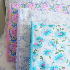 Peut inclure: Quatre taies d'oreiller avec des motifs floraux. La taie d'oreiller du haut a un motif floral rose et bleu. La deuxi&egrave;me taie d'oreiller a un motif floral bleu clair. La troisi&egrave;me taie d'oreiller a un fond blanc avec un motif floral bleu et rose. La taie d'oreiller du bas a un fond blanc avec un motif floral bleu.