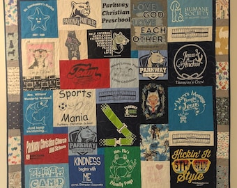 May include: A colorful quilt made from t-shirts with various designs and text. The quilt features a variety of colors, including blue, green, red, and white. The text on the t-shirts includes phrases such as "Parkway Christian School", "Jesus is our Anchor", "Sports Mania", and "Kickin' It 5th Grade Style".