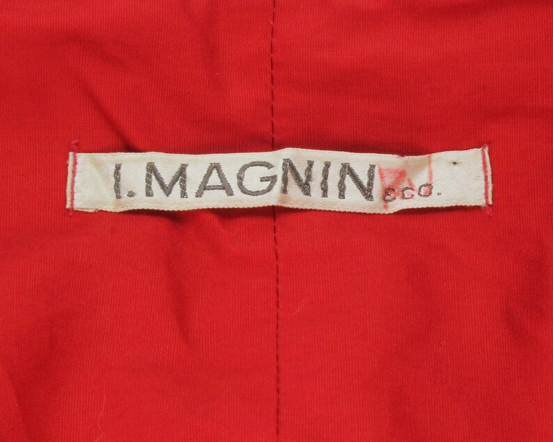 May include: A white label with the text "I. MAGNIN & CO." in black lettering.